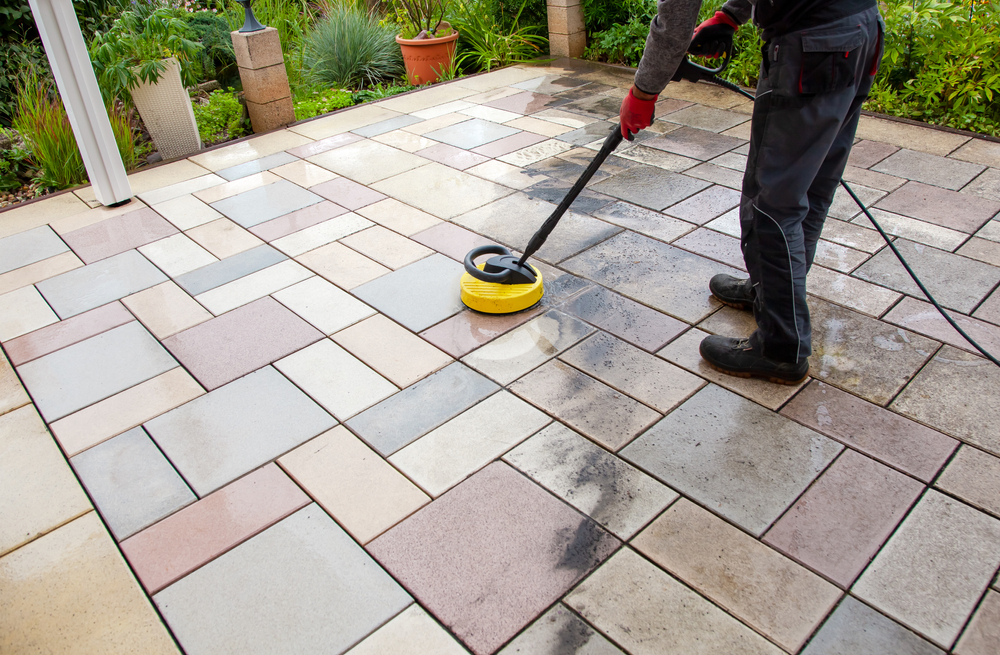 Cleaning stone slabs on patio with the high-pressure cleaner. Person worker cleaning the outdoors floor. clean and dirty