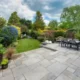 Beautiful summer garden in England, UK with lawn and large, indian sandstone patio.
