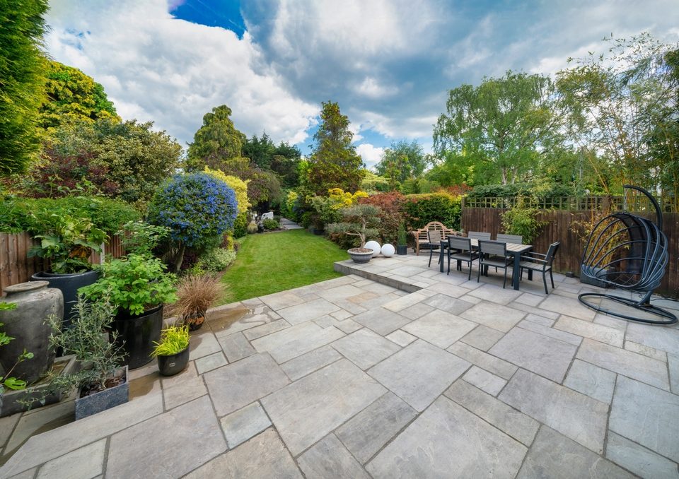 Beautiful summer garden in England, UK with lawn and large, indian sandstone patio.