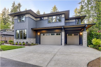 New construction home exterior with contemporary house plan features gray wood siding, stone columns and two garage spaces. Northwest, USA