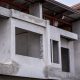 unfinished building with exposed concrete structures, open window frames, and partial roofing, indicating ongoing construction work.