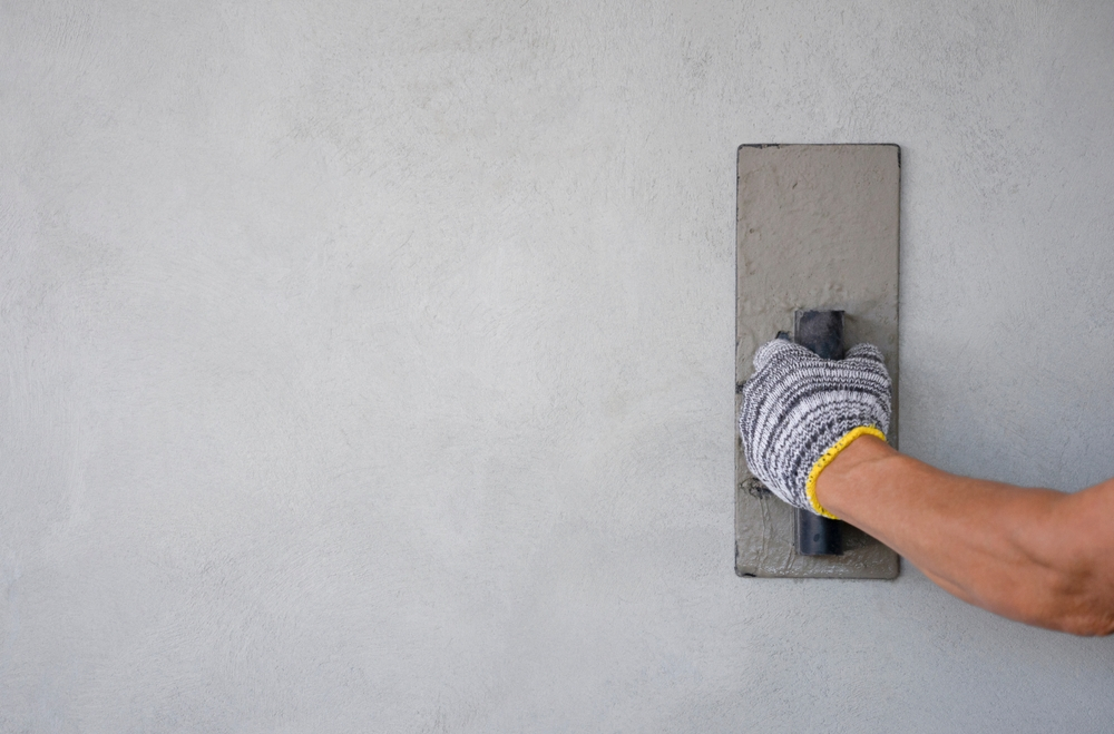 concept of wall plastering, structural work, plaster work, home building,building wall. worker hand wears glove holding trow