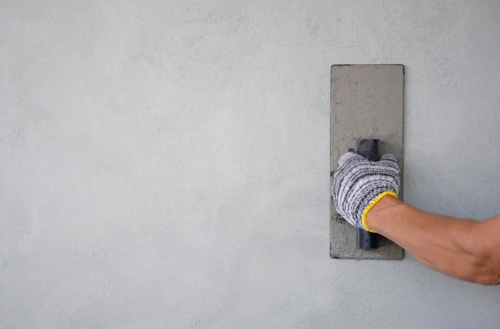 concept of wall plastering, structural work, plaster work, home building,building wall. worker hand wears glove holding trow