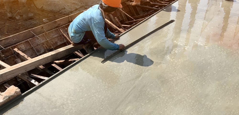 man hand spreading concrete mix with trowel in foundation. A construction worker is pouring cement and concrete,