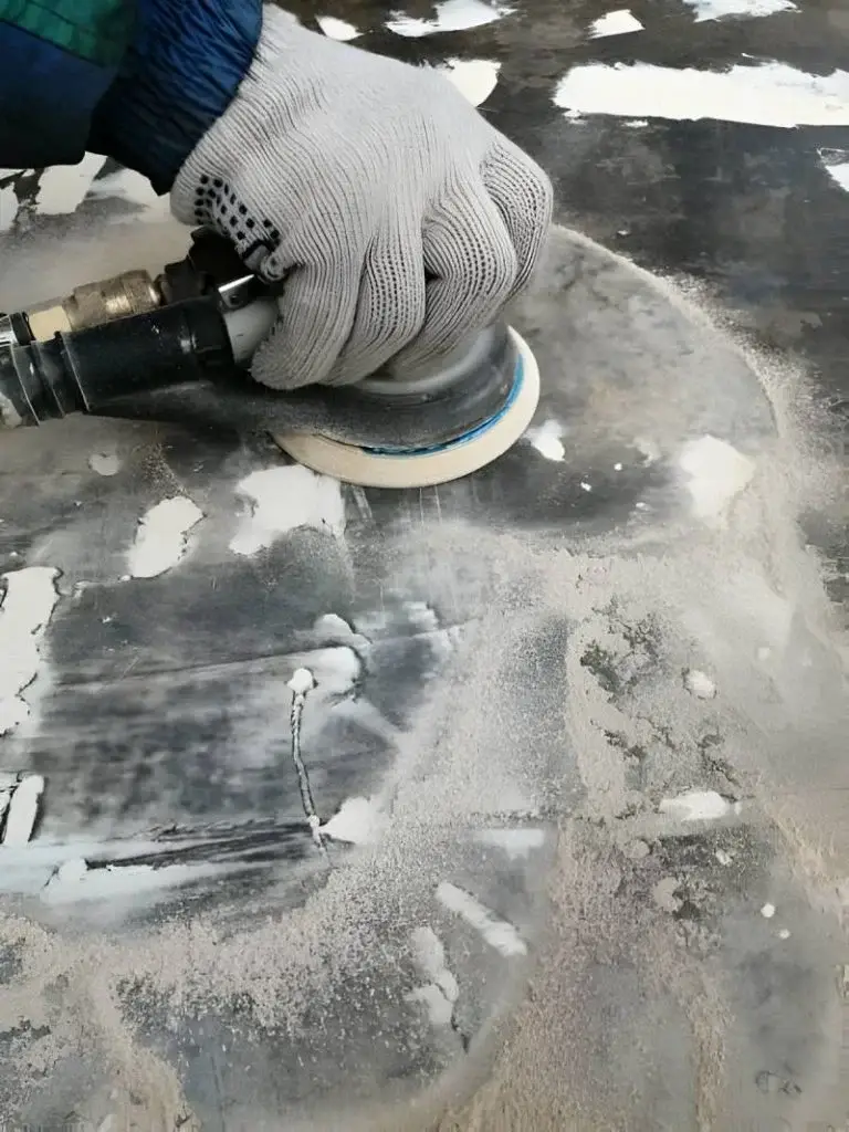 Work with a pneumatic orbital machine in a hand in a white glove on a dark putty surface